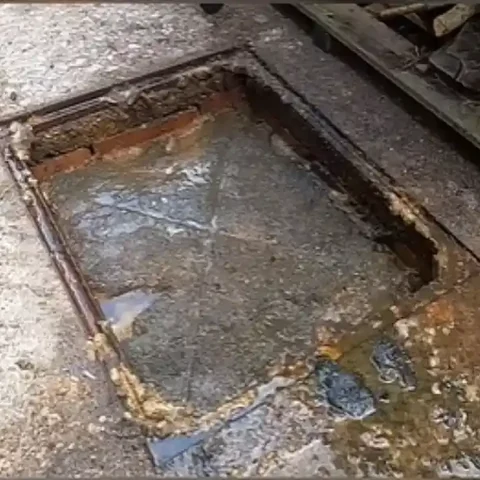 Clogged floor drain before cleaning Brick-lined floor drain full of standing water and greasy buildup before cleaning